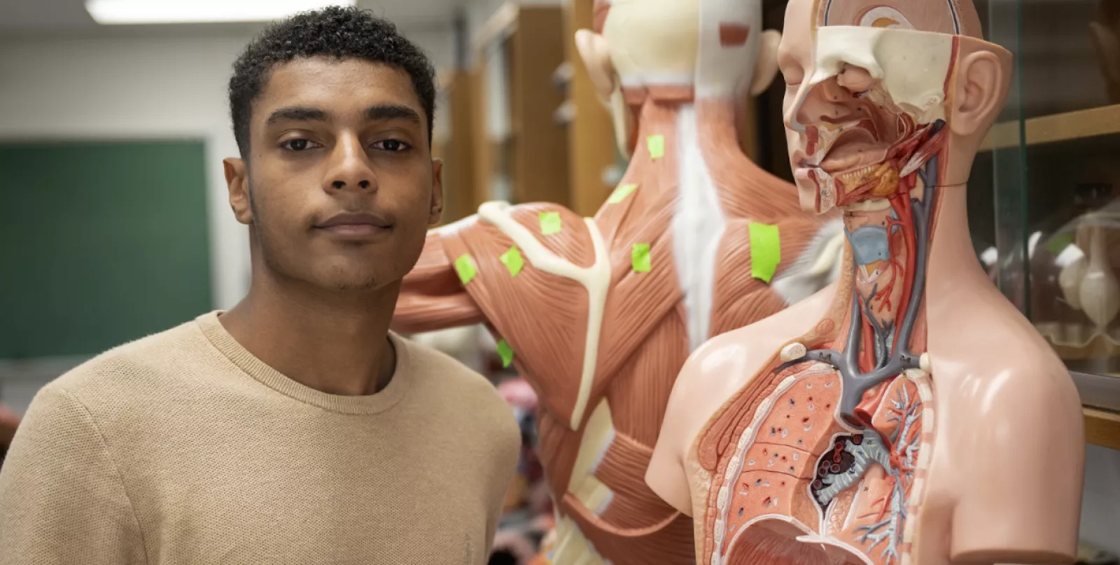 student looking at camera with medical model