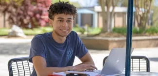 male student studying in the quad