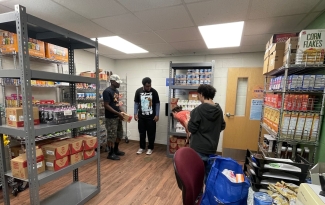 Three people standing in a room with shelves of food on display