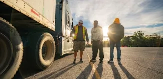 Three men standing beside a tractor trailer