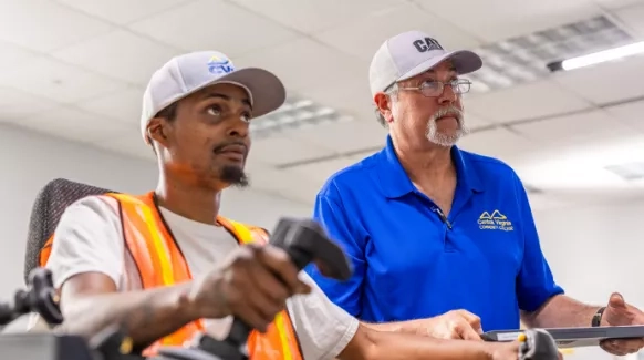 Two people wearing ballcaps focused on something off screen to the right