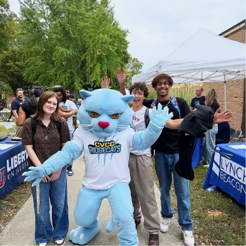 The CVCC mascot standing on a sidewalk with a group of students behind him