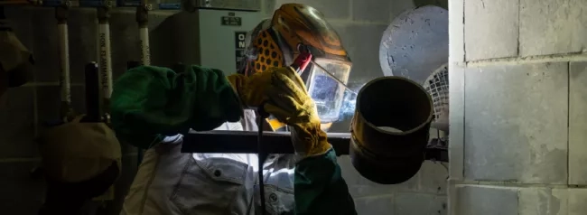 A person wearing protective gear while welding a joint.