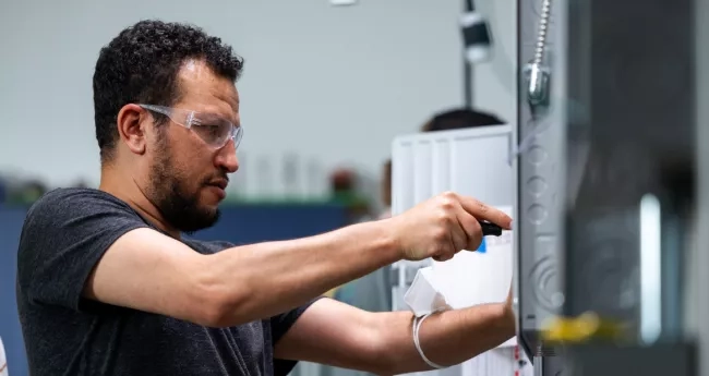 Male electrical student using a screwdriver