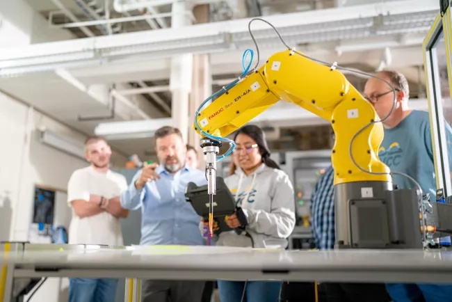 mechatronics students and instructor with robot arm