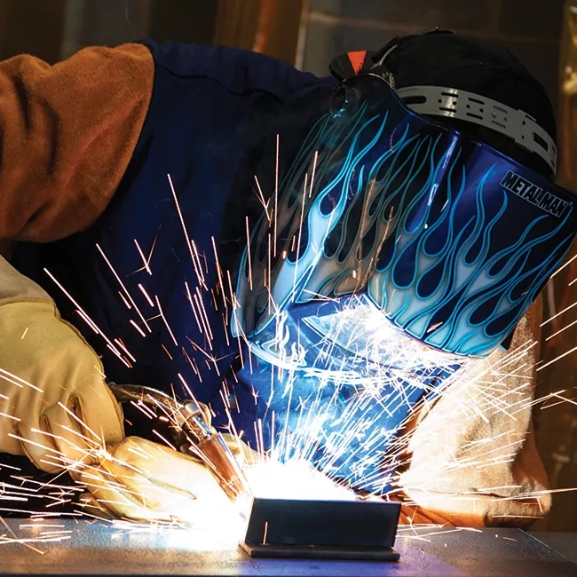A person wearing a welder's mask and using a welder